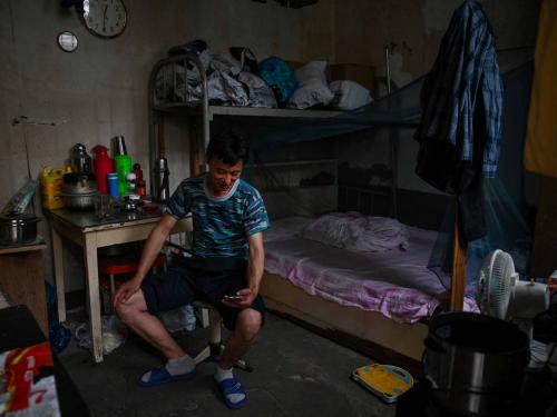 This photo taken on June 21, 2022 shows a deliveryman in his room in the Laoximen neighbourhood of Shanghai's Huangpu district. - Bricked-up doorways, crumbling facades, and a small group of defiant locals: one of Shanghai's oldest neighbourhoods is barely clinging to life as the city presses ahead with demolition and redevelopment plans. (Photo by Hector RETAMAL / AFP)