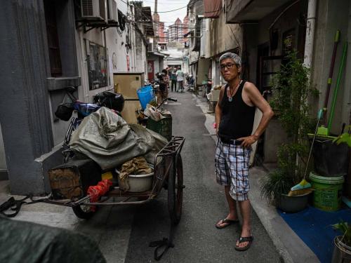 This photo taken on June 21, 2022 shows a man looking on in an alley while other residents move furniture out of their homes, to be demolished for new development, in the Laoximen neighbourhood of Shanghai's Huangpu district. - Bricked-up doorways, crumbling facades, and a small group of defiant locals: one of Shanghai's oldest neighbourhoods is barely clinging to life as the city presses ahead with demolition and redevelopment plans. (Photo by Hector RETAMAL / AFP)