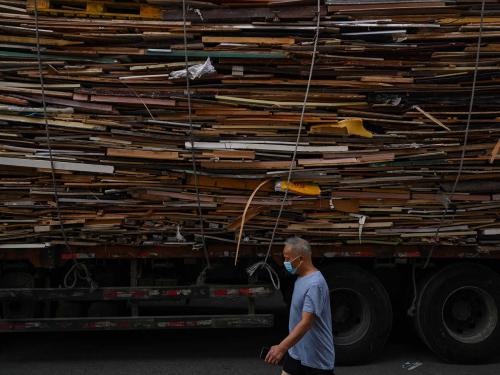 This photo taken on June 22, 2022 shows a man walking past a truck loaded with timber from demolished houses in the Laoximen neighbourhood of Shanghai's Huangpu district. - Bricked-up doorways, crumbling facades, and a small group of defiant locals: one of Shanghai's oldest neighbourhoods is barely clinging to life as the city presses ahead with demolition and redevelopment plans. (Photo by Hector RETAMAL / AFP)