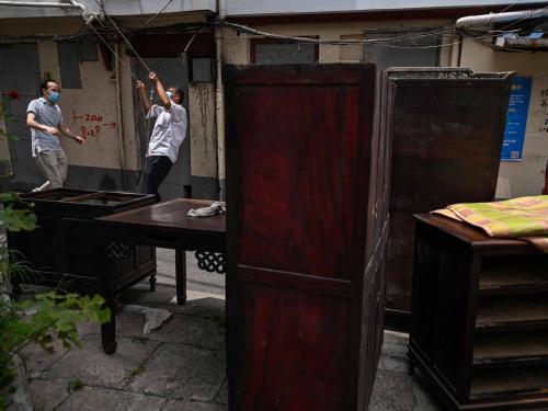 This photo taken on June 21, 2022 shows residents moving furniture out of their homes, to be demolished for new development, in the Laoximen neighbourhood of Shanghai's Huangpu district. - Bricked-up doorways, crumbling facades, and a small group of defiant locals: one of Shanghai's oldest neighbourhoods is barely clinging to life as the city presses ahead with demolition and redevelopment plans. (Photo by Hector RETAMAL / AFP)