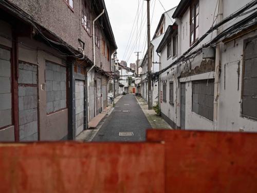 This photo taken on June 21, 2022 shows a street with sealed buildings marked for demolition in the Laoximen neighbourhood of Shanghai's Huangpu district. - Bricked-up doorways, crumbling facades, and a small group of defiant locals: one of Shanghai's oldest neighbourhoods is barely clinging to life as the city presses ahead with demolition and redevelopment plans. (Photo by Hector RETAMAL / AFP)