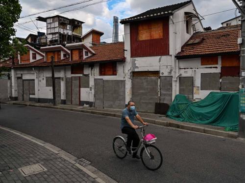 This photo taken on June 22, 2022 shows a man riding a bicycle past sealed buildings marked for demolition in the Laoximen neighbourhood of Shanghai's Huangpu district. - Bricked-up doorways, crumbling facades, and a small group of defiant locals: one of Shanghai's oldest neighbourhoods is barely clinging to life as the city presses ahead with demolition and redevelopment plans. (Photo by Hector RETAMAL / AFP)