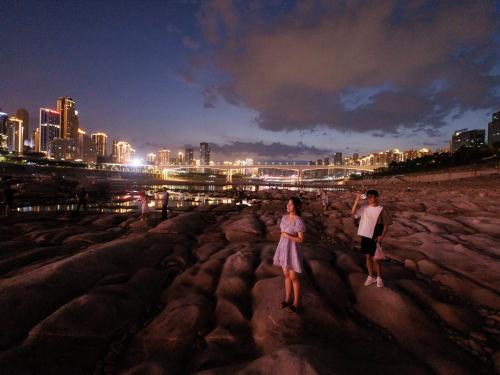 Mensen kijken naar de skyline vanaf de droge rivierbedding van de terugtrekkende Jialing rivier, een zijrivier van de Yangtze, die een recordlaag waterpeil nadert tijdens een regionale droogte in Chongqing, China op 20 augustus, 2022. @Reuters