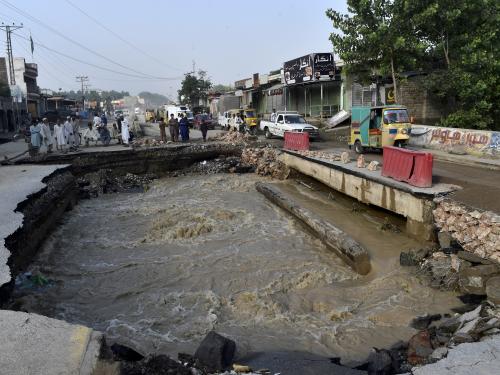 Residents gather beside a road damaged by flood waters following heavy monsoon rains in Charsadda district of Khyber Pakhtunkhwa on August 29, 2022. - The death toll from monsoon flooding in Pakistan since June has reached 1,061, according to figures released on August 29, 2022, by the country's National Disaster Management Authority. (Photo by Abdul MAJEED / AFP)