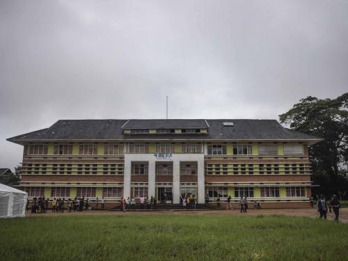 People stand in front of the administrative building of the National Institute for Agronomic Study and Research (INERA) in Yangambi, 100 km from the city of Kisangani, in the province of Tshopo, in the northeast of the Democratic Republic of the Congo on September 2, 2022. - The site, renowned during the time of Belgian colonisation for its research in tropical agronomy, hosts a herbarium that has more than 6000 species. (Photo by Guerchom Ndebo / AFP)