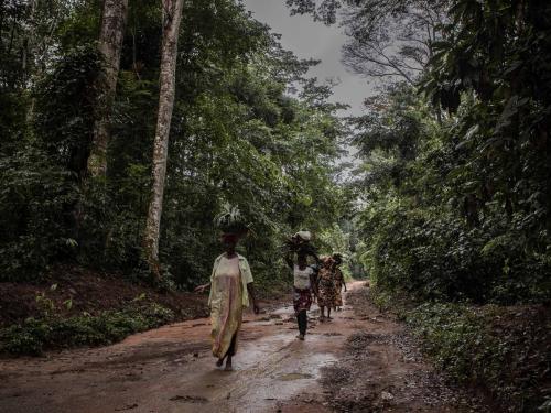 People walk along a road covered by primary forest in Yangambi Biosphere Reserve, 100 km from the city of Kisangani, in Tshopo Province, northeastern Democratic Republic of Congo, on September 2, 2022. (Photo by Guerchom Ndebo / AFP)