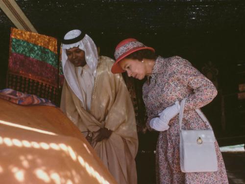 British Royal Queen Elizabeth II, wearing a floral print outfit with a red safari helmet-style hat, with a floral band to match the outfit, during a walkabout with a Saudi guide, location unspecified, in Saudi Arabia, February 1979. The British Royals are on a tour of the Gulf States. (Photo by Tim Graham Photo Library via Getty Images)