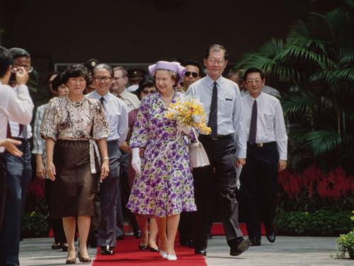 British Royal Queen Elizabeth ll, wearing a lilac, green and white outfit with a Philip Somerville hat, carrying a bouquet of flowers during a visit to Townsville Primary School, part of her visit to Singapore, 10th October 1989. The Royal couple is on a three-day official visit to Singapore, en route to Malaysia, where the Queen opens the Commonwealth Heads of Government Meeting on 18th October. (Photo by Tim Graham Photo Library via Getty Images)