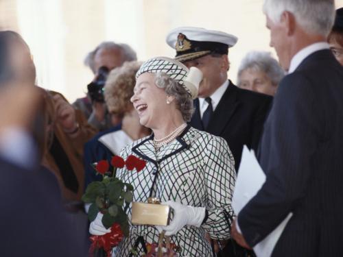 Queen Elizabeth II laughing while holding a small bouquet of flowers before boarding the Royal yacht Britannia in Portsmouth, Hampshire, England, Great Britain, 6 August 1992. Britannia was to leave Portsmouth on a cruise of the Western Isles for the Royal summer holiday.  (Photo by Tim Graham Photo Library via Getty Images)