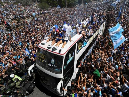 TOPSHOT - Fans of Argentina cheer as the team parades on board a bus after winning the Qatar 2022 World Cup tournament in Buenos Aires, Argentina on December 20, 2022. - Millions of ecstatic fans are expected to cheer on their heroes as Argentina's World Cup winners led by captain Lionel Messi began their open-top bus parade of the capital Buenos Aires on Tuesday following their sensational victory over France. (Photo by Luis ROBAYO / AFP) (Photo by LUIS ROBAYO/AFP via Getty Images)