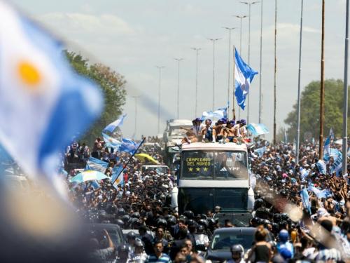 TOPSHOT - Fans of Argentina cheer as the team parades on board a bus after winning the Qatar 2022 World Cup tournament, in Buenos Aires province, on December 20, 2022. - Millions of ecstatic fans are expected to cheer on their heroes as Argentina's World Cup winners led by captain Lionel Messi began their open-top bus parade of the capital Buenos Aires on Tuesday following their sensational victory over France. (Photo by TOMAS CUESTA / AFP) (Photo by TOMAS CUESTA/AFP via Getty Images)
