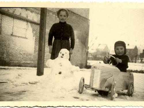 Monique en Jacques Devos, kinderen van Roger en Maria Delbeke, spelen in de sneeuw. Beiden poseren ze fier en warm ingeduffeld bij de sneeuwman die ze bouwden, Jacques in zijn Torck trapauto.