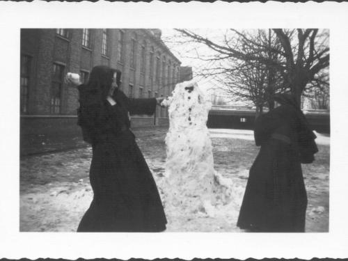 Zuster M.-Lutgardis gooit een sneeuwbal naar een andere zuster op de speelplaats van de Sint-Jozefsschool langs de Meenseweg.
