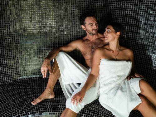 Smiling couple is sitting in a private sauna on their vacation in a luxury villa.