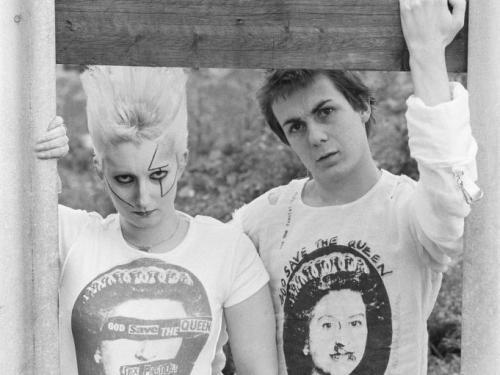 Kleding van de Seditionaries shop op King's Road in Londen, 1977. Pamela Rooke (1955 - 2022), aka Jordan en Simon Barker, aka Six, tonen de Sex Pistols 'God Save The Queen' T-shirts.