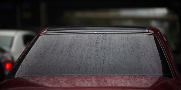 Vitre arrière d'une voiture sous la pluie, sans essuie-glace arrière.