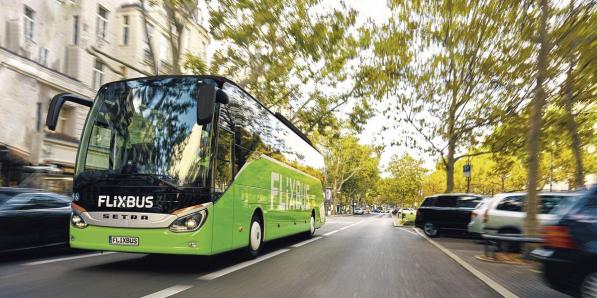 Un des bus verts de FlixBus roulant dans une rue arborée