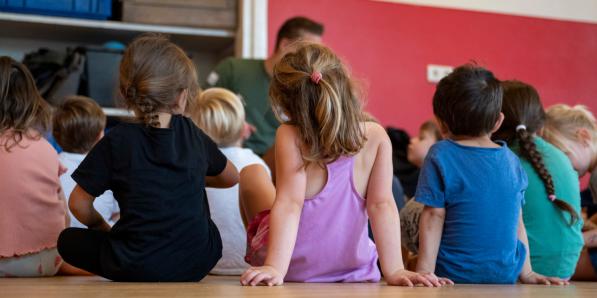 Man speelt met kleuters in kinderopvanglocatie in Vlaanderen.