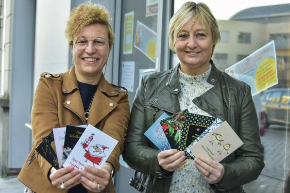 Zaakvoerster Vanessa Neyrinck en medewerkster Ann Vanheede met de kerstkaarten waarmee je niet alleen de drukkerij, maar ook de vier jeugdbewegingen steunt. (foto LVW)