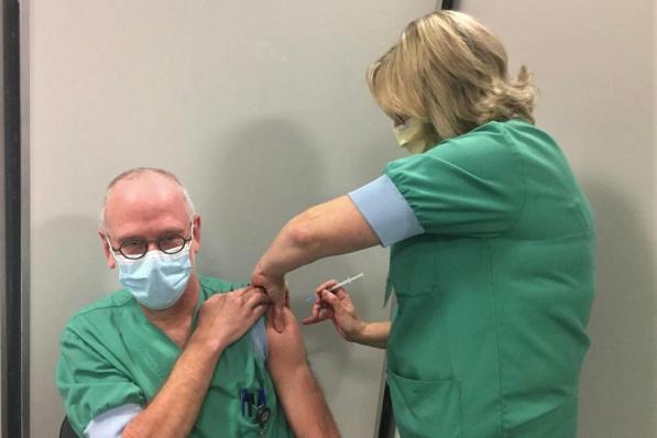 Hoofdverpleegkundige Intensieve Zorgen Veerle Desmedt zet de spuit met het coronavaccin bij Johan Tamsin.© (Foto MVQ)