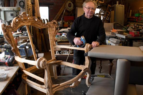 Ghislain met enkele meubels die hij restaureert in zijn atelier.© RB