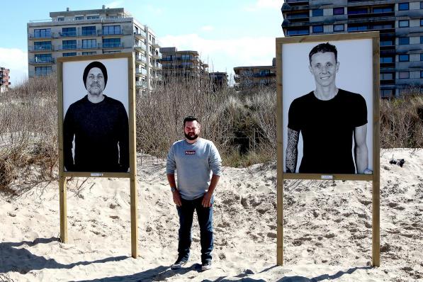 Frank Lambrechts tussen de portretten van de broers Gert en Sam Bettens op ‘t strand van De Panne.© PADI/Daniël