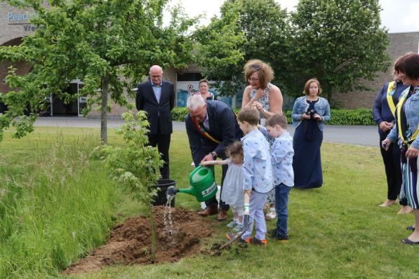 Burgemeester Evrard helpt water geven aan de pas geplante boom onder het goedkeurend oog van de Ierse ambassadeur.© Eric Flamand