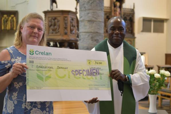 Pastoor Sylvester is dolgelukkig met de cheque voor het herstel van de basisschool in zijn geboortedorp. (foto AV)