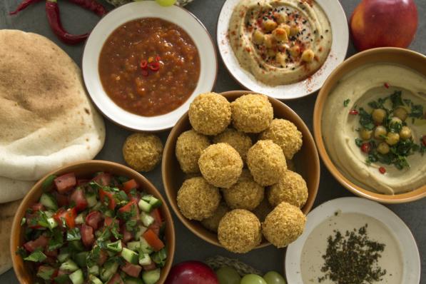 Authentic food of Israel: hummus, falafels, pita bread and fresh fruits. Dark grey background with copy space. Healthy eating concept.