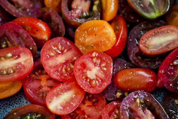 Close-up of a bowl of halved cherry tomatoes seasoned with pepper.