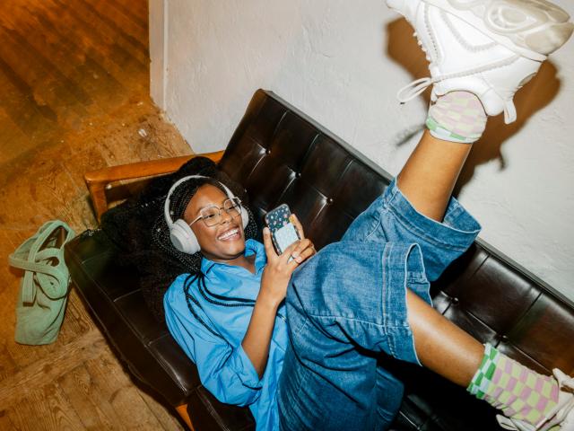 femme canapé casque et téléphone, jambes en l'air