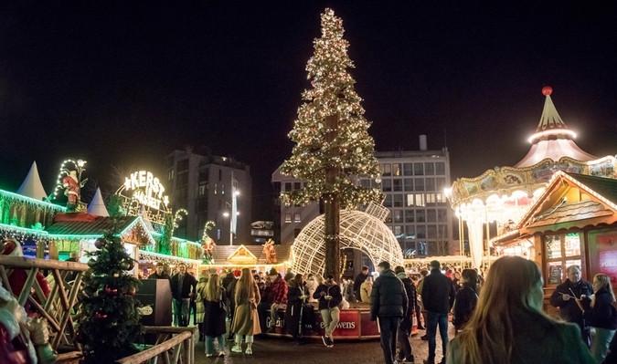Zicht op kerstmarkt met attracties en versierde kerstboom