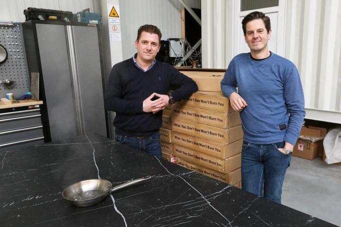 Daevy Nuyttens (links) en Pieter Van Hecke, de zaakvoerders van Cimajet, demonstreren de onzichtbare kookplaat in hun atelier op het bedrijventerrein.©Johan Sabbe