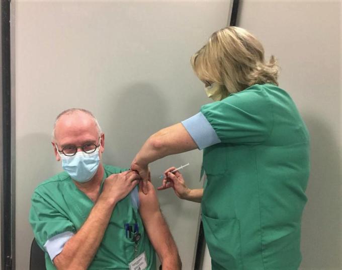 Hoofdverpleegkundige Intensieve Zorgen Veerle Desmedt zet de spuit met het coronavaccin bij Johan Tamsin.© (Foto MVQ)