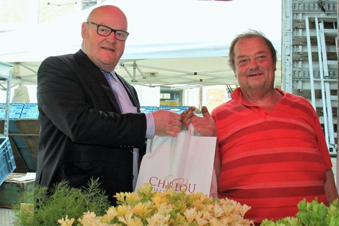 Romain Bekaert (rechts) werd hier in 2014 in de bloemetjes gezet door toenmalig Kortrijks schepen Rudolf Scherpereel (N-VA) voor vijftig jaar dienst op Kortrijkse maandagmarkt. (foto JVGK)