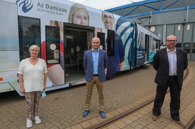 Directieleden van AZ Zeno, AZ Damiaan en AZ West voor een tram met foto's van zorgmedewerkers.©Peter MAENHOUDT