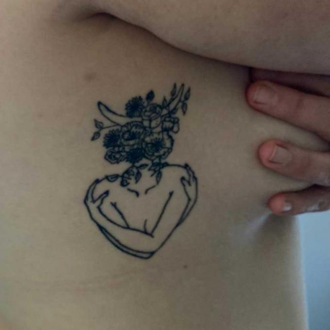 De tattoo van de vrouw die zichzelf omarmt.
