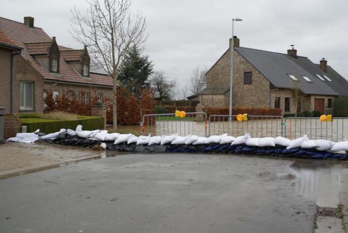 Een dijk van zandzakjes dwars over de Kormbekestraat moet verhinderen dat er nog meer water het dorp binnenloopt.