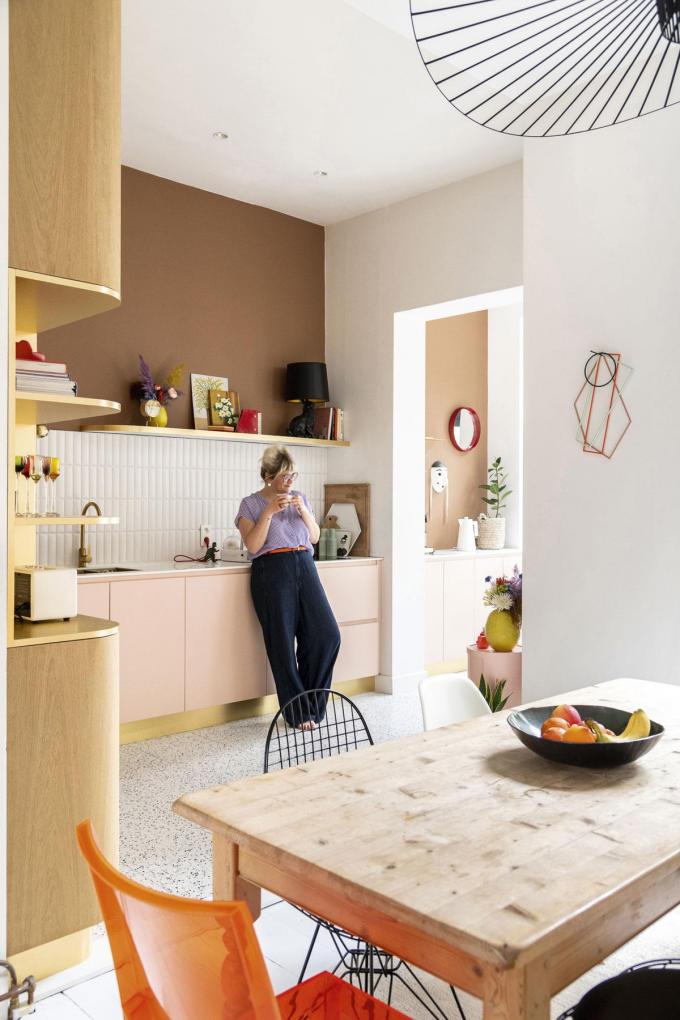 La cuisine rose aux détails dorés est une création de Studio Boîte. A l’aide de deux nuances marron aux murs, Jasmien lui a conféré un twist funky. La lampe de table noire est le luminaire Rabbit de Moooi. Les tableaux proviennent d’un magasin de seconde main.