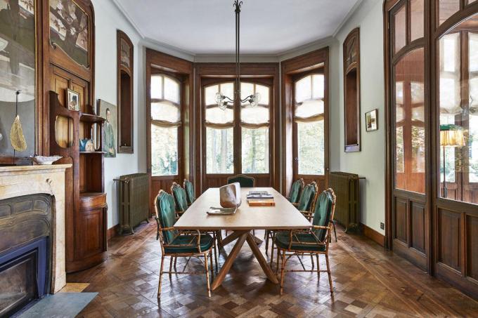 Dans la salle à manger, à droite de la cheminée, Horta a dessiné un meuble passe-plat qui pivote vers l’arrière-cuisine. Encadrant la cheminée, les toiles murales peintes par Albert Ciamberlani.