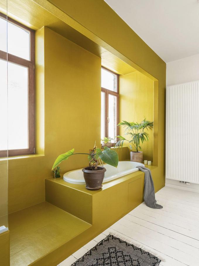 Un élément en polyester jaune curry unifie l’aménagement de la salle de bains en formant un meuble à part entière.