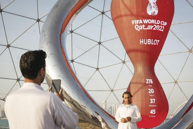 Trois travailleurs pakistanais devant le monument symbole de la Coupe du monde de football au Qatar et son décompte avant le coup d’envoi.