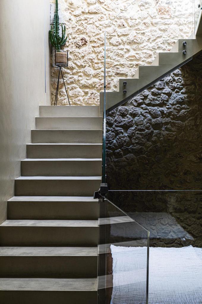 De oude bakstenen muur vormt een mooi contrast met de moderne betonnen trap en glazen wand.
