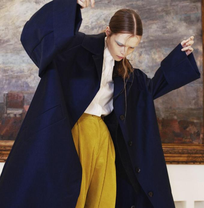 Manteau overzised en coton bleu foncé, Christian Wijnants. Blazer en laine, Julia June. Chemise en coton blanc, Gigue. Pantalon en velours côtelé ocre, Essentiel.