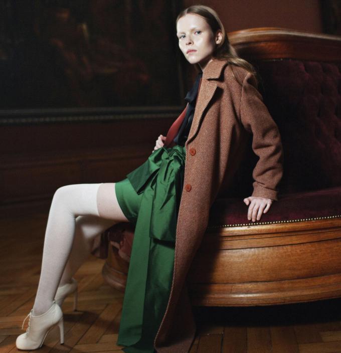 Manteau en laine rouille, Marie Méro. Blouse en viscose noire, L’histoire de Louise by E5 mode. Blazer rouille, HER. Minijupe en viscose verte, Bernadette. Bas écrus, Falke. Chaussures en cuir blanc, Dries Van Noten.