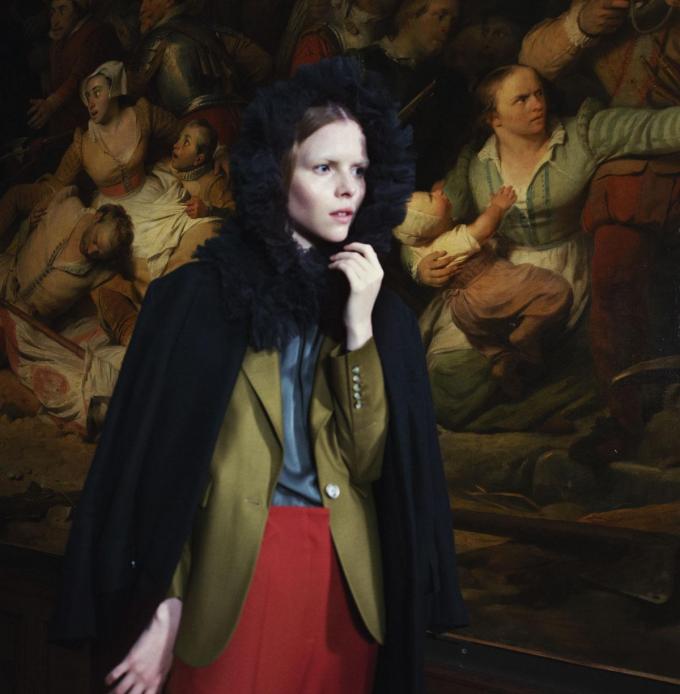 Manteau en laine noire, Façon Jacmin. Blazer kaki, Xandres. Blouse en viscose verte, Nathalie Vleeschouwer. Pantalon en viscose et polyester rouille, Caroline Biss. Masque en dentelle noire, Matthew Schell.