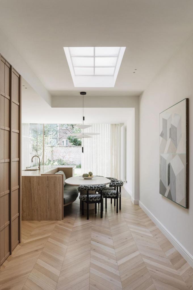 La cuisine, avec son coin repas, donne sur le jardin. Les meubles et les revêtements rembourrés aux formes arrondies sont parfaitement adaptés aux enfants. Au mur, se trouve une œuvre de Charline Tyberghein.