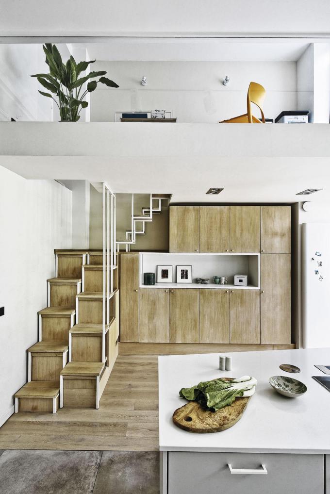 Dans la pièce à vivre, un espace bureau en mezzanine exploite la hauteur sous plafond. L’escalier sur mesure intègre des éléments de rangement réalisé par un ferronnier artisan (Fero Inox).