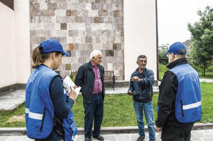 Europese monitoren Nina en Raymond leggen hun missie uit aan inwoners van Tegh. ‘Contact met de zwaarbewapende Russen proberen we te vermijden.’