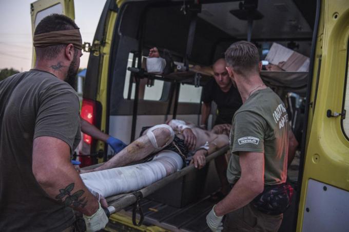 De gewonde soldaten worden op brancards van de bestelwagen naar de hospitaalbus overgebracht.